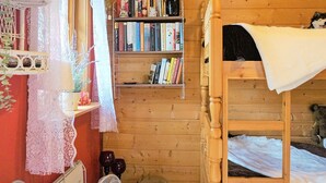 A wooden bunk bed room with a bookshelf, lace curtains, and a fan. - 4 Person Holiday Home in Tibro (Tibro)