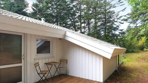 A wooden deck with a sliding glass door, a small table, two chairs, and a window. - Holiday Home in Saltum (Saltum)