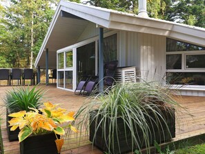Uma casa moderna com varanda, mobiliário de exterior e vasos de plantas.