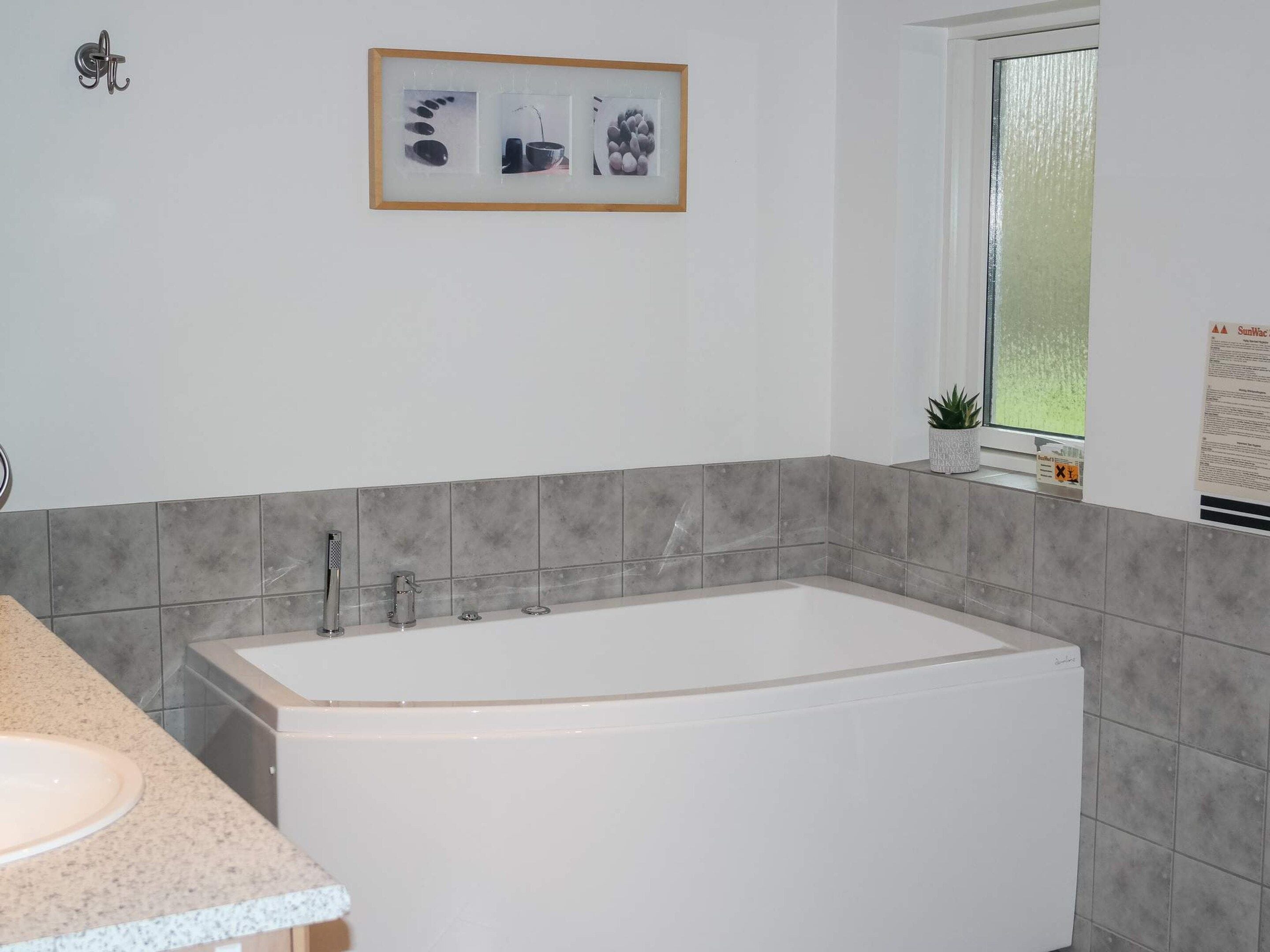 A bathroom with a bathtub, a sink, and a window.