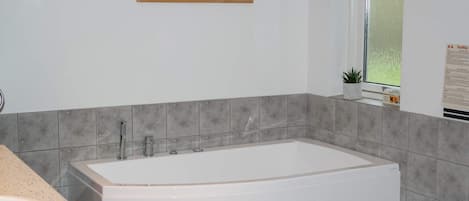 Une salle de bain avec une baignoire, un lavabo et une fenêtre.