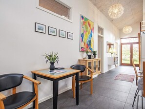 A modern interior with a dining area, a large abstract painting, and a view through a glass door.