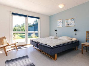 A bedroom with a bed, a chair, a desk, and a view through a sliding door to the outdoors. - 8 Person Holiday Home in Lokken (Lokken)