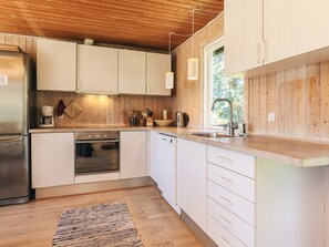 A modern kitchen with wooden cabinets, stainless steel appliances, and a large window providing natural light. - 8 Person Holiday Home in Lokken (Lokken)