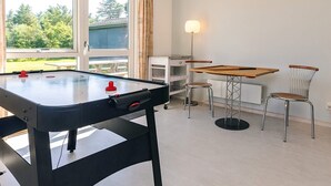 Una mesa de billar con taburetes, una lámpara y una ventana con cortinas.