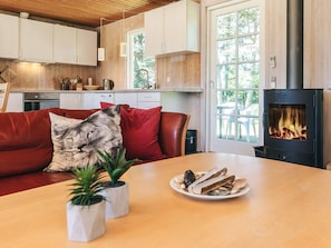 A cozy living room with a sofa, a fireplace, and a dining table with a plate of food. - 8 Person Holiday Home in Lokken (Lokken)