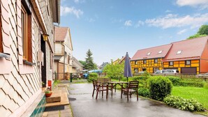 Une cour avec une table et des chaises, une pelouse verdoyante et des bâtiments à l’architecture traditionnelle.