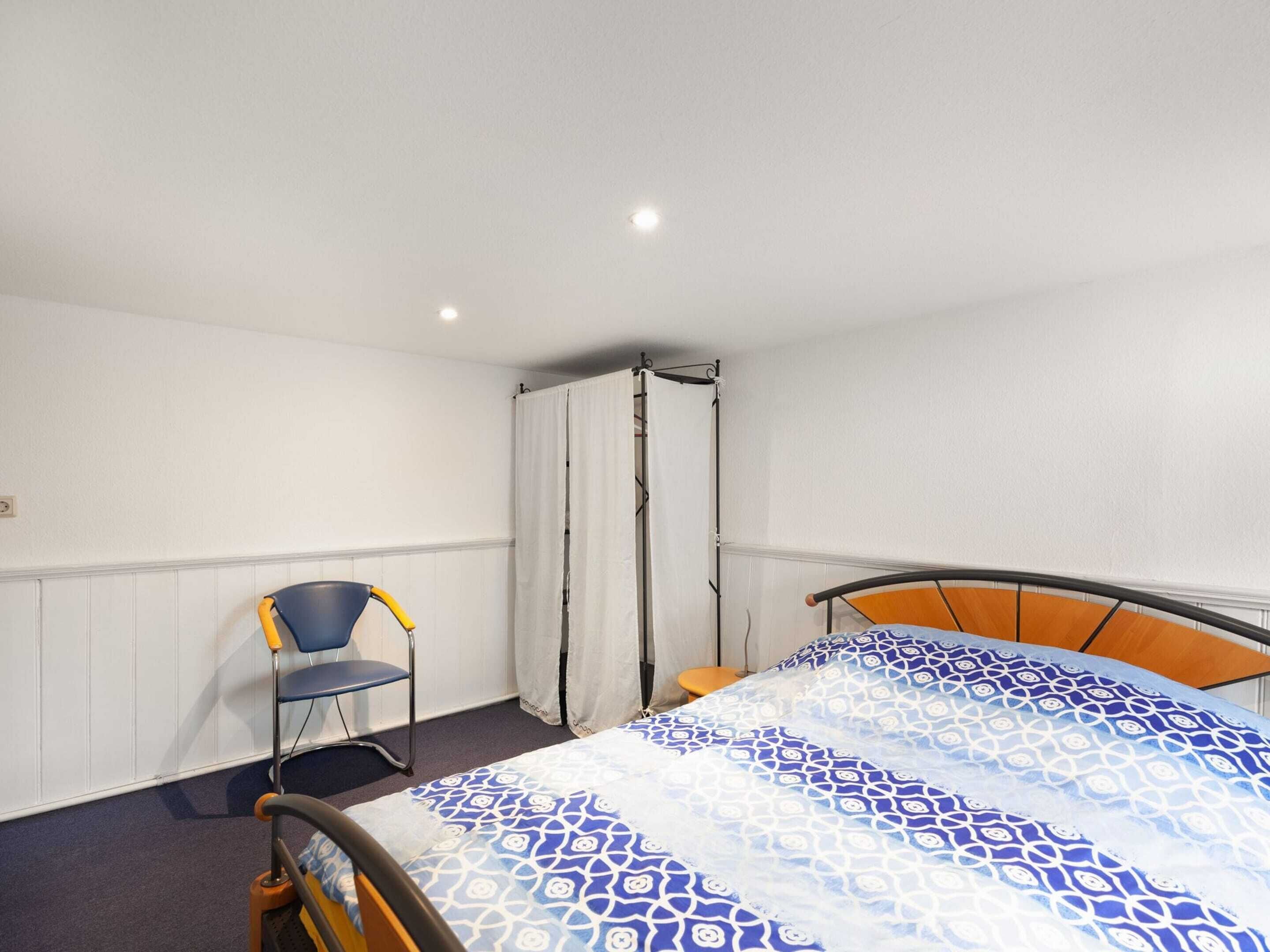 Un dormitorio con cama, una silla y una cortina.