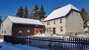 Un quartier résidentiel enneigé avec deux maisons : l’une est recouverte de bois à l’extérieur et l’autre présente une façade en briques.