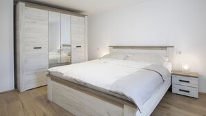 A bedroom with a wooden bed, a wardrobe with mirrored doors, a bedside table, and a nightstand. - Modern Holiday Home With Jacuzzi (Medulin)