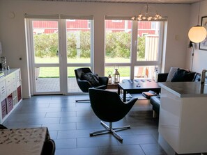 Eine moderne Küche mit Essbereich, großen Schiebeglastüren zu einem Garten und Blick auf ein rotes Gebäude.