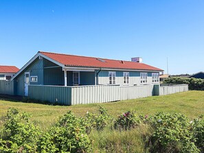 A single-story house with a red roof and a porch, surrounded by a fenced yard. - Holiday Home in LÃ¸kken (Lokken)