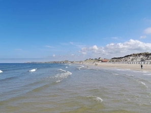 A beach with waves, a sandy shore, and a few people. - Holiday Home in LÃ¸kken (Lokken)