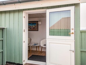 A room with a door, a small table, two chairs, and a framed picture on the wall. - Holiday Home in LÃ¸kken (Lokken)