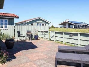 A patio area with outdoor furniture, a potted plant, and a wooden fence. - Holiday Home in LÃ¸kken (Lokken)
