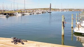 A marina with boats docked at wooden piers, a lighthouse in the distance, and calm water. - 5 Person Holiday Home in Varobacka (Väröbacka)
