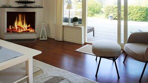 A living room with a fireplace, a view of the outdoors, and a cozy seating area. - 5 Person Holiday Home in Varobacka (Väröbacka)