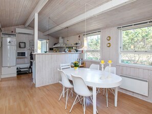 A compact kitchen with a dining area, wooden floors, and a view through the window.
