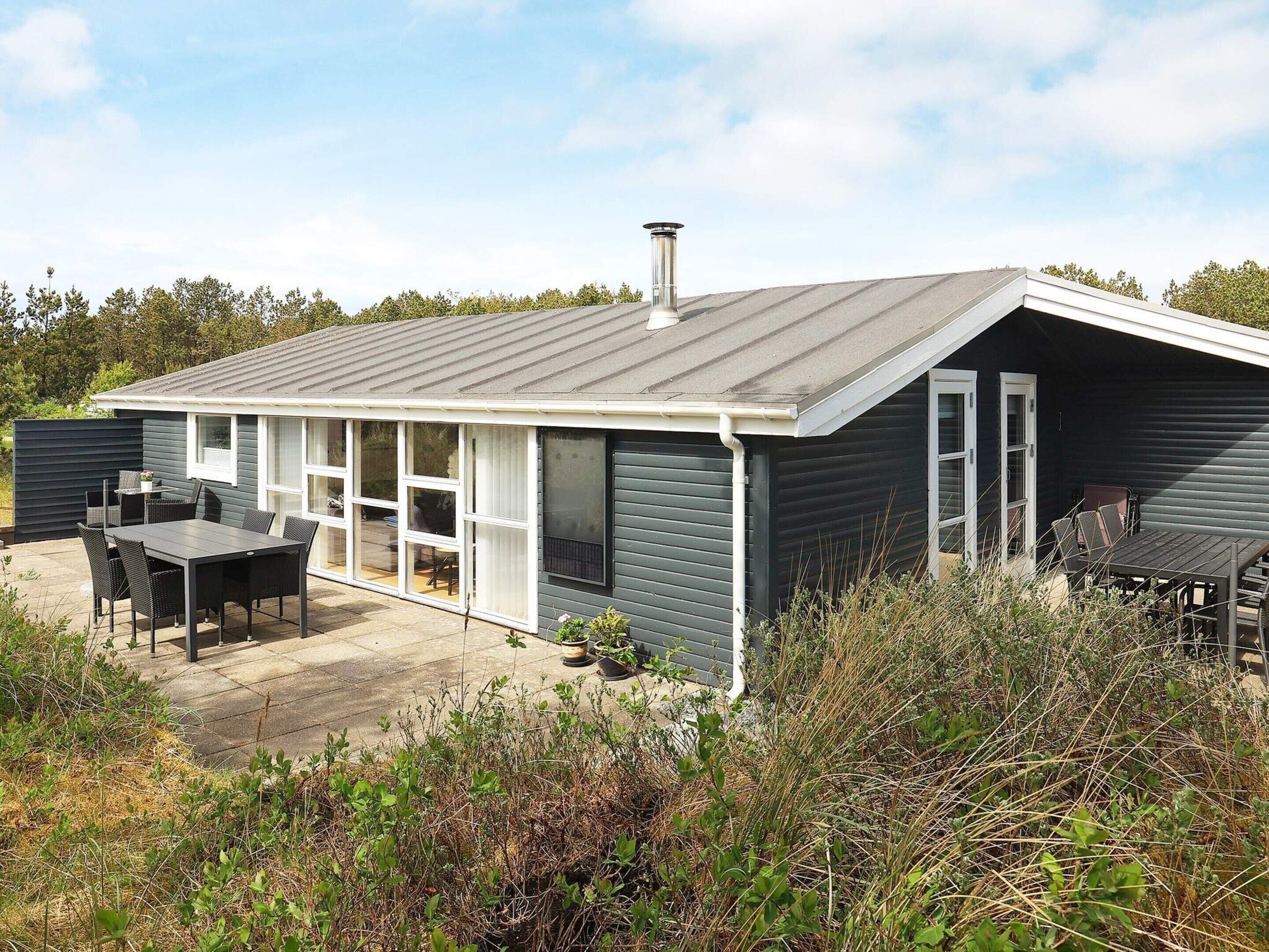 A modern house with a large patio, sliding glass doors, and a chimney.