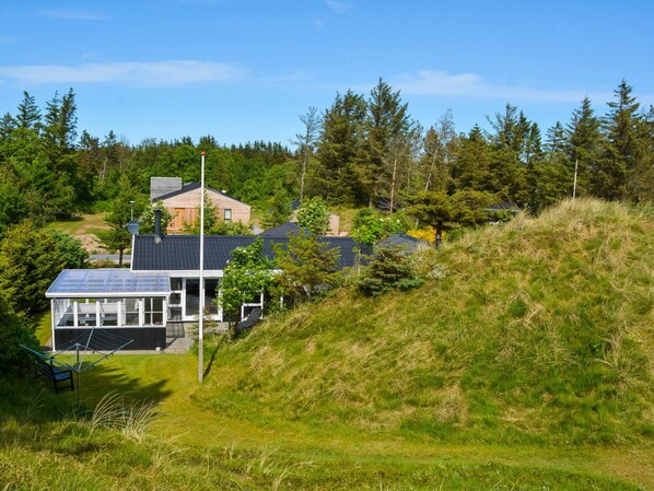A modern house with solar panels, surrounded by lush greenery and trees.