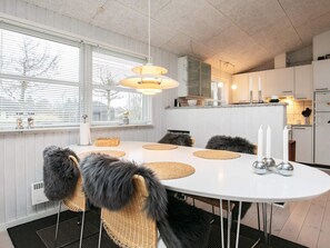 A modern dining area with a round table, chairs with fur accents, and a hanging light fixture.