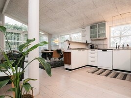 A modern kitchen with white cabinets, a dining area with a table and chairs, and large windows providing natural light.