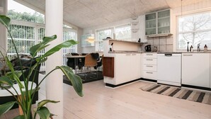 A modern kitchen with white cabinets, a dining area with a table and chairs, and large windows providing natural light.