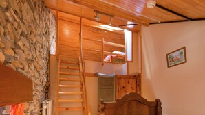 A bedroom with a wooden ladder leading to a loft bed, a stone wall, and a small window. - Renovated Farmhouse From 1832 With Beautiful View of Winter Sports Area (Vielsalm)