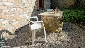 A stone table with a chair and bottles, set against a stone wall with a window. - Renovated Farmhouse From 1832 With Beautiful View of Winter Sports Area (Vielsalm)