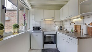 Eine moderne Küche mit weißen Schränken, einem Bosch-Kühlschrank, einer Mikrowelle, einem Backofen und einem Spülbecken.