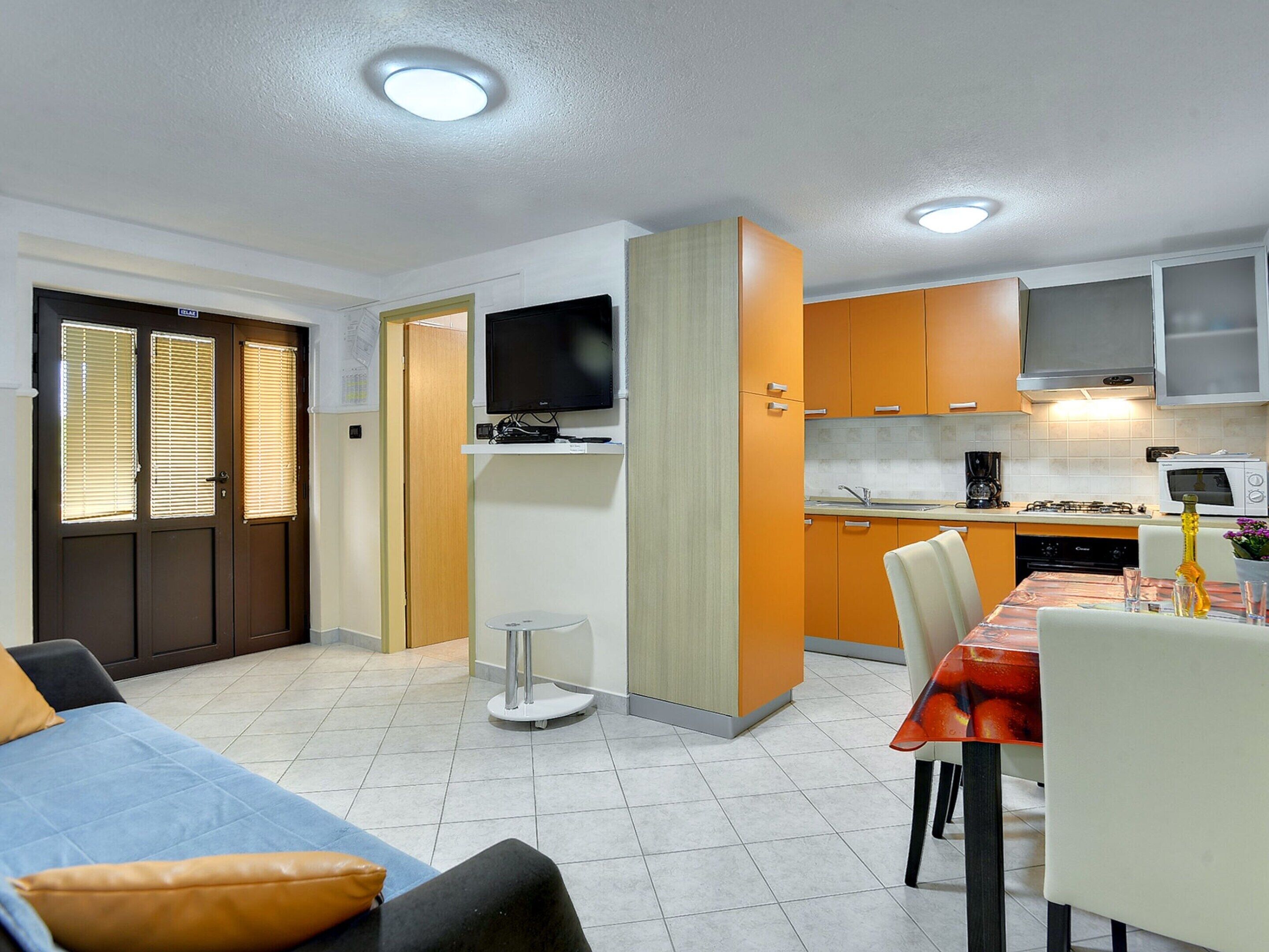 A compact living space with a kitchenette, a dining area, and a seating area with a sofa and chairs.