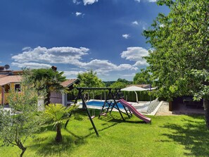 A backyard with a swing set, a slide, and a swimming pool. - Villa in Baksi With Pool and Playground (Pazin)