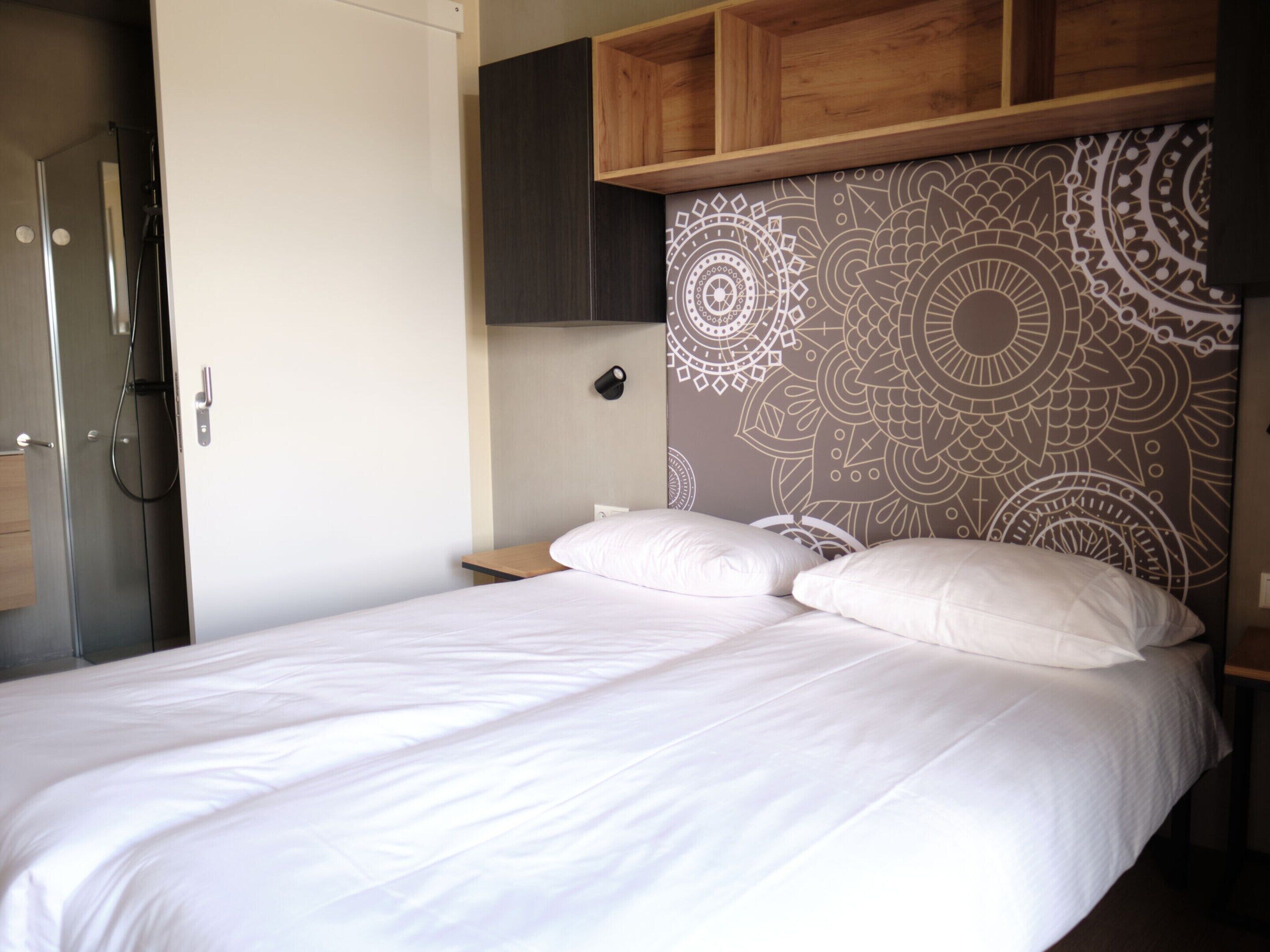 A bedroom with a bed, a wooden headboard, a nightstand, and a wardrobe.