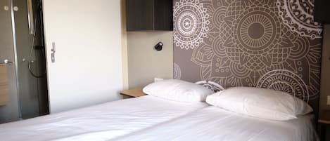 A bedroom with a bed, a wooden headboard, a nightstand, and a wardrobe.