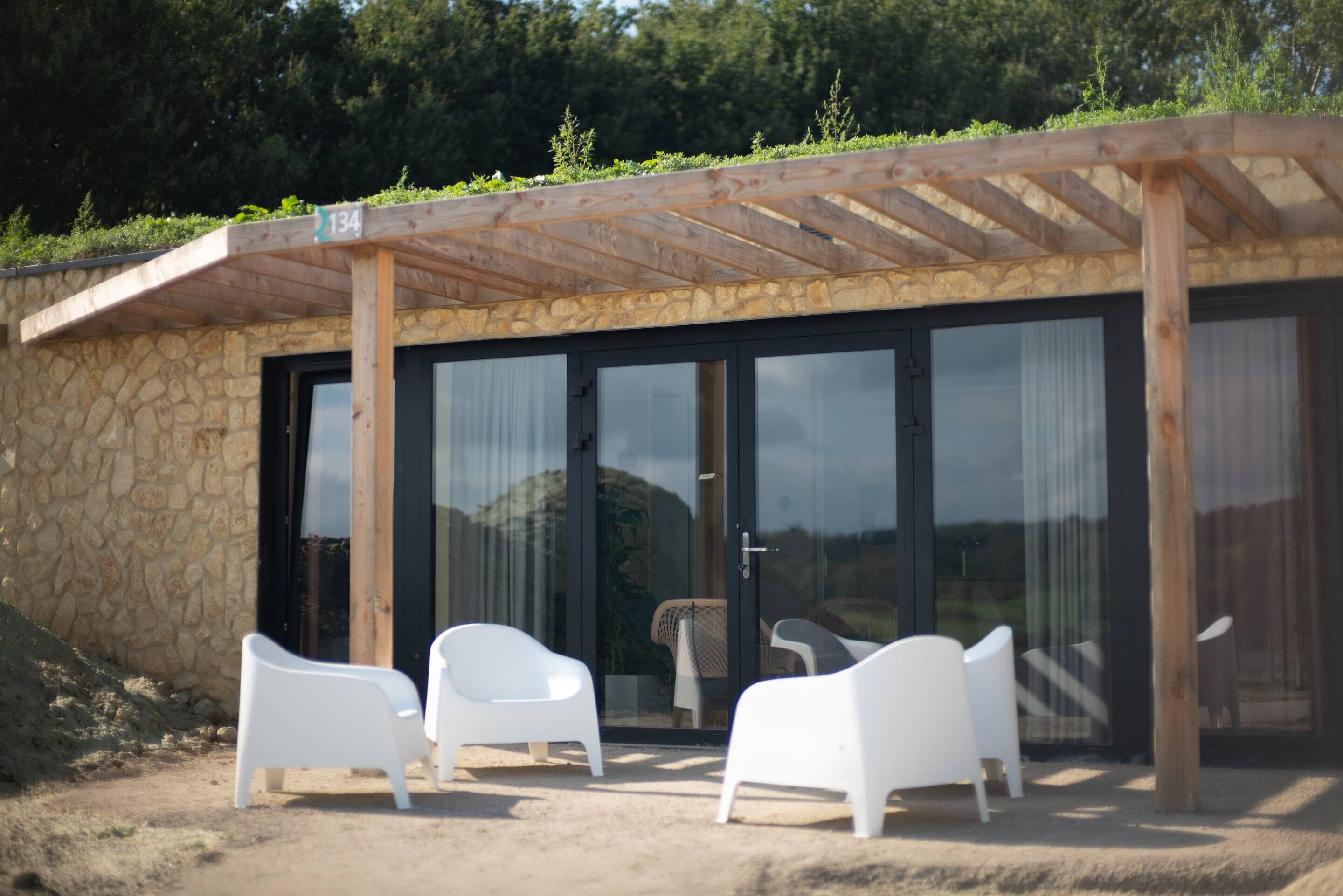 Et overdækket udendørs opholdsområde med stenvægge og en træpergola.