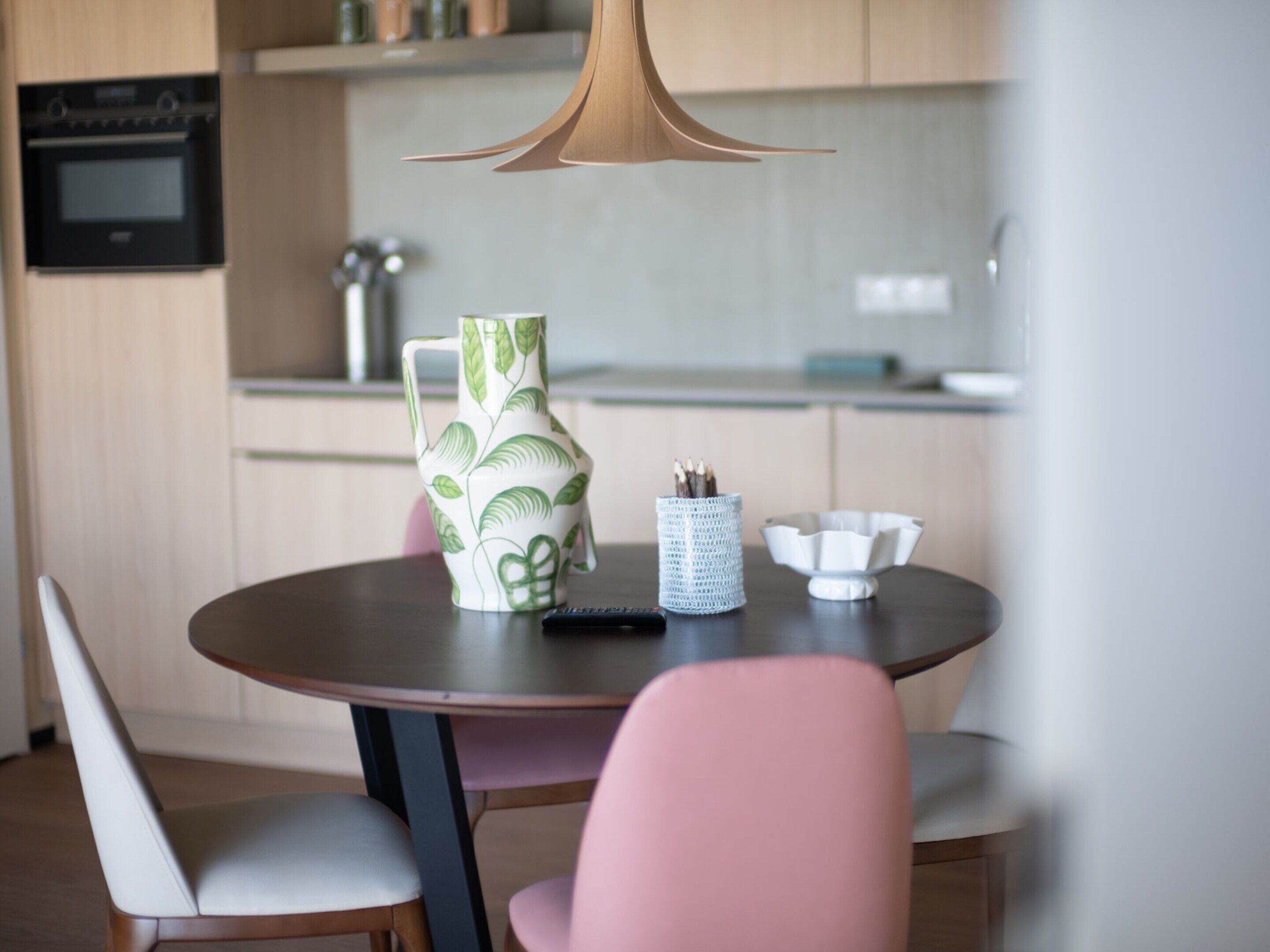 A modern kitchen with a round table, a coffee maker, and a vase.