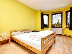 A room with a wooden bed, yellow walls, and large windows.