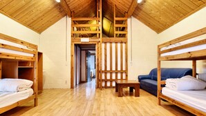 Un dormitorio con literas de madera, una pequeña mesa de madera y un sofá azul.