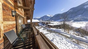 Un edificio in legno con un balcone affacciato su un paesaggio innevato e montagne.