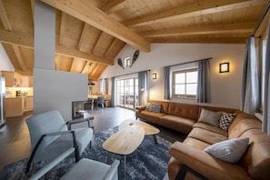 A spacious living area with a high ceiling, a sofa set, a coffee table, and a dining area with a view. - Restful Chalet in Wald-Königsleiten near Ski Bus (Wald im Pinzgau)