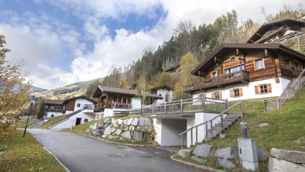 Tipico chalet in legno con una scala in pietra e un ponte che collega a un altro edificio.