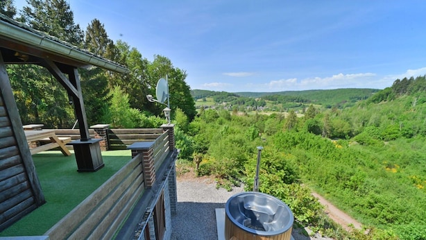 A wooden cabin with a deck, a hot tub, and a scenic view of a valley. - Chalet in Beffe With Hot Tub & Valley Views (Rendeux)