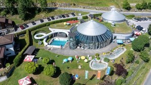 Un grand bâtiment circulaire doté d’une piscine, entouré d’un parking et d’espaces verts.