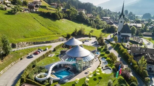 A resort with a pool, a water slide, and a church in the background.