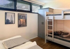 A bunk bed room with a grey wardrobe, two framed pictures on the wall, and a window with blinds. - Chalet Retreat With Sauna in Wald (Wald im Pinzgau)