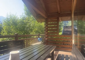 Une terrasse en bois avec un banc et une structure vitrée.