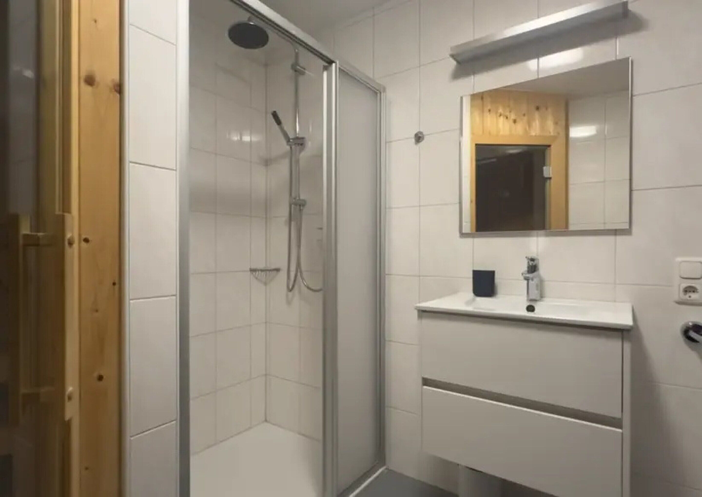 A bathroom with a glass-enclosed shower, a white sink, and a mirror above it.