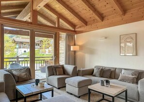 A modern interior with a wooden ceiling, a sofa set, a coffee table, and a view of a building through large windows. - Chalet Retreat With Sauna in Wald (Wald im Pinzgau)