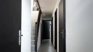 Um corredor com escadas, portas e uma luminária no teto.