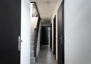 A hallway with a staircase, doors, and a ceiling light. - Chalet Retreat With Sauna in Wald (Wald im Pinzgau)